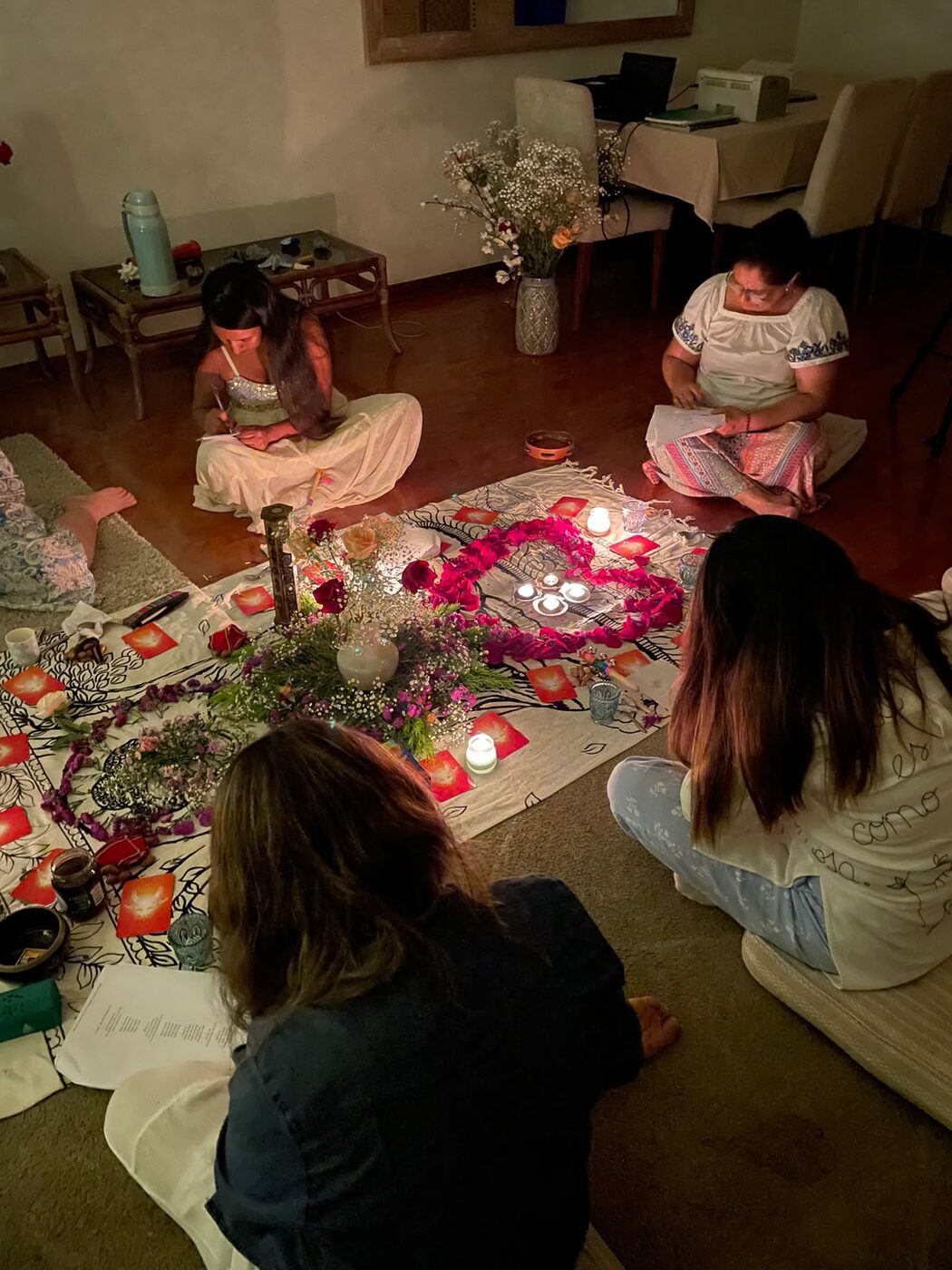 Mujeres escribiendo sus intenciones alrededor del altar a la luz de las velas
