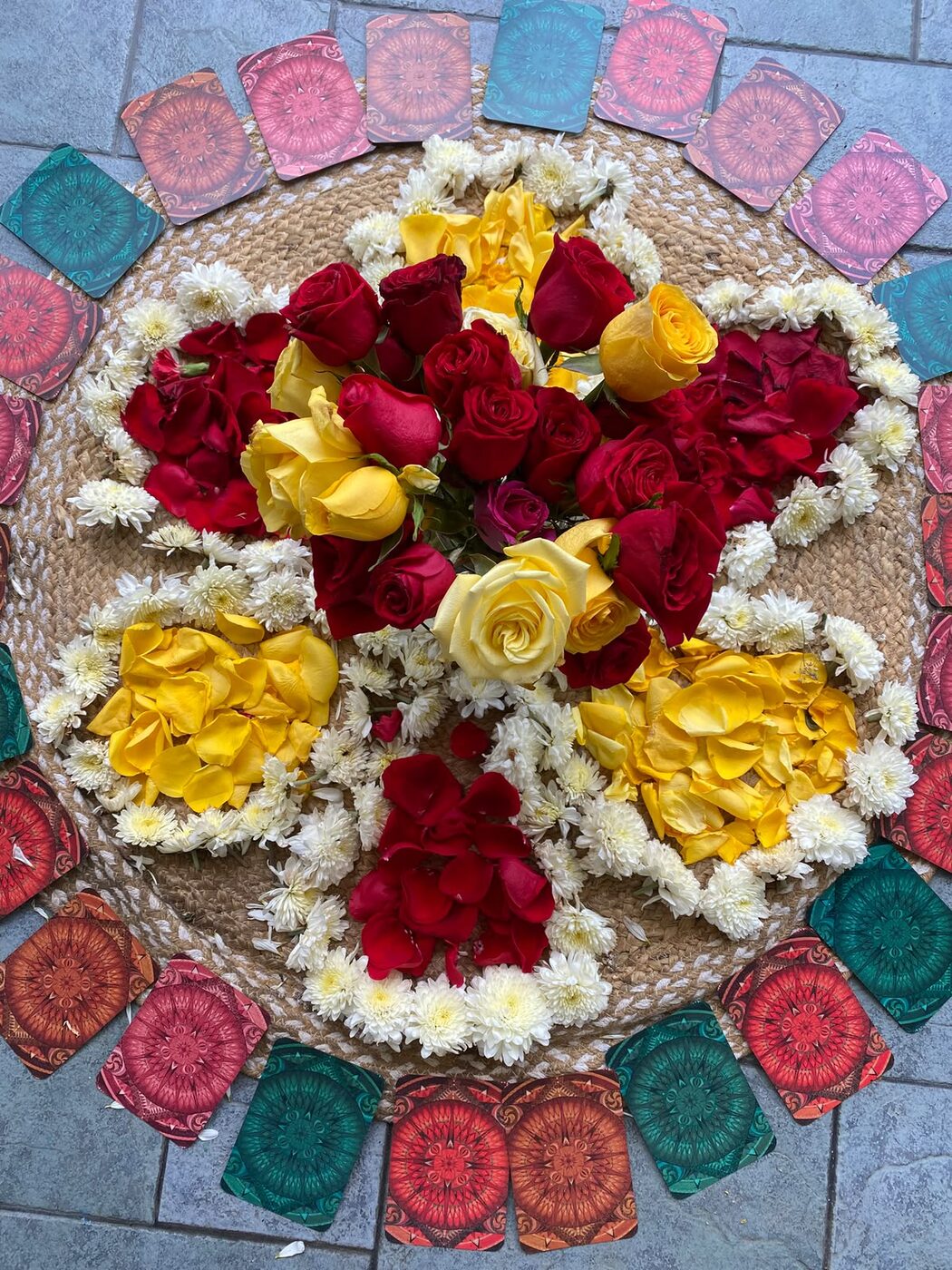Mandala de rosas rojas y amarillas rodeado de cartas en el suelo
